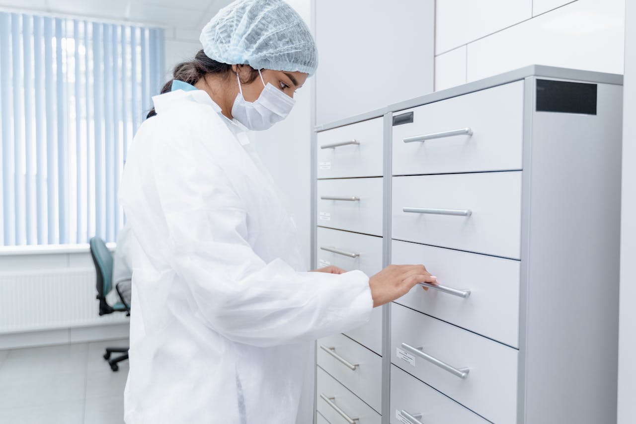 about-01 A medical professional in a lab coat organizes files in a sterile clinic environment, focusing on healthcare organization.